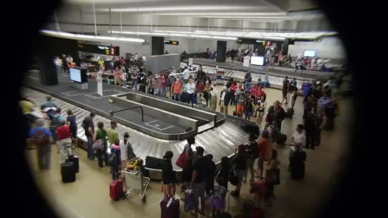 Airport Baggage Carousel Crowded By Travelers.webp